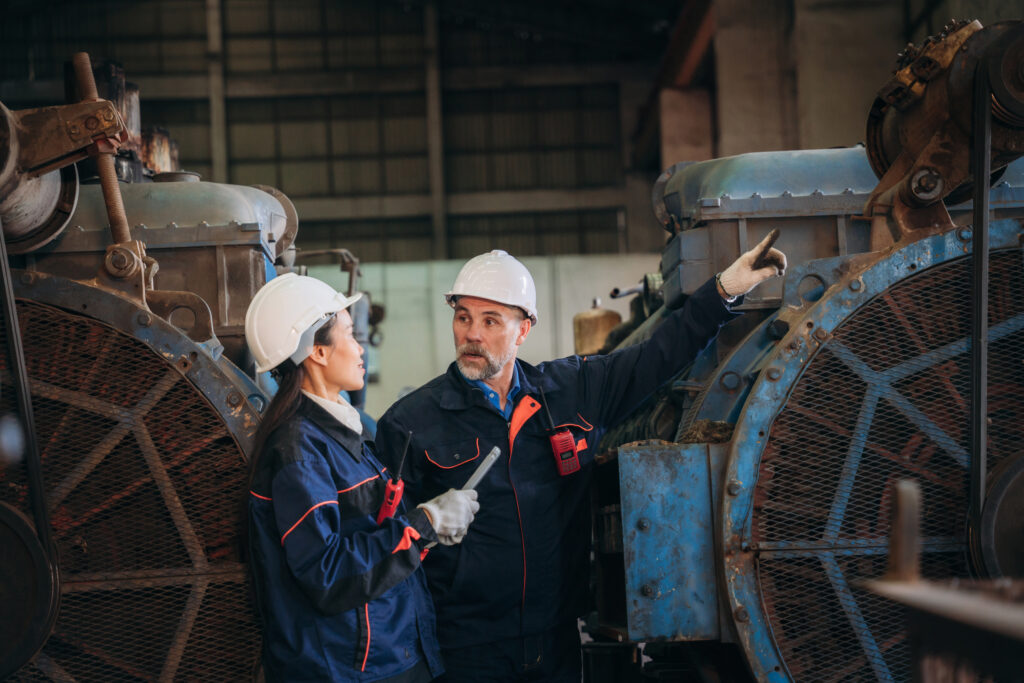Engineer Are Working In The Factory. Worker Helping To Repair And Inspect The Machine's Readiness. Mechanical Technicians Are Maintaining The Engine That Is Malfunctioning.